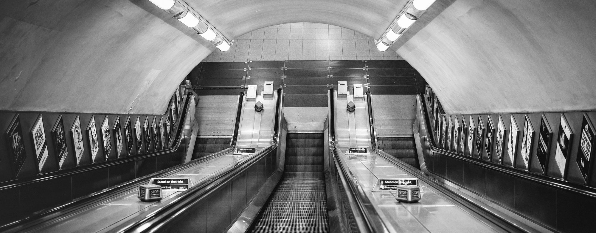 Black-and-white photograph of escalators in a London Underground station